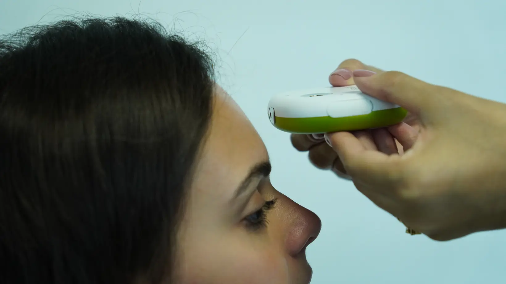 Aferição em uma paciente com dispositivo médico conectado apoiado na testa, em perfil, durante o atendimento