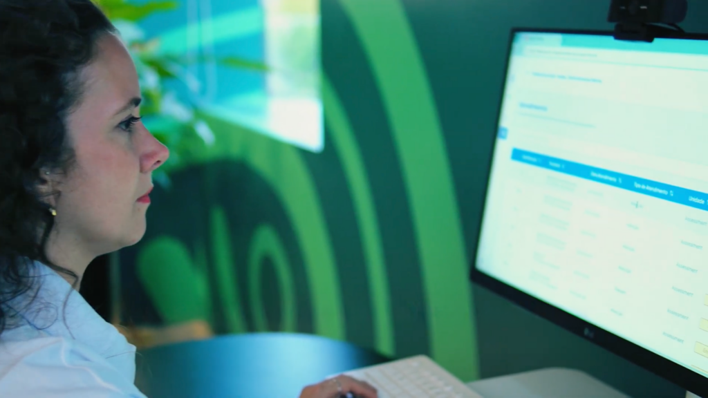 Profissional de saúde utilizando uma plataforma digital em computador para acompanhar informações clínicas do paciente em ambiente assistido